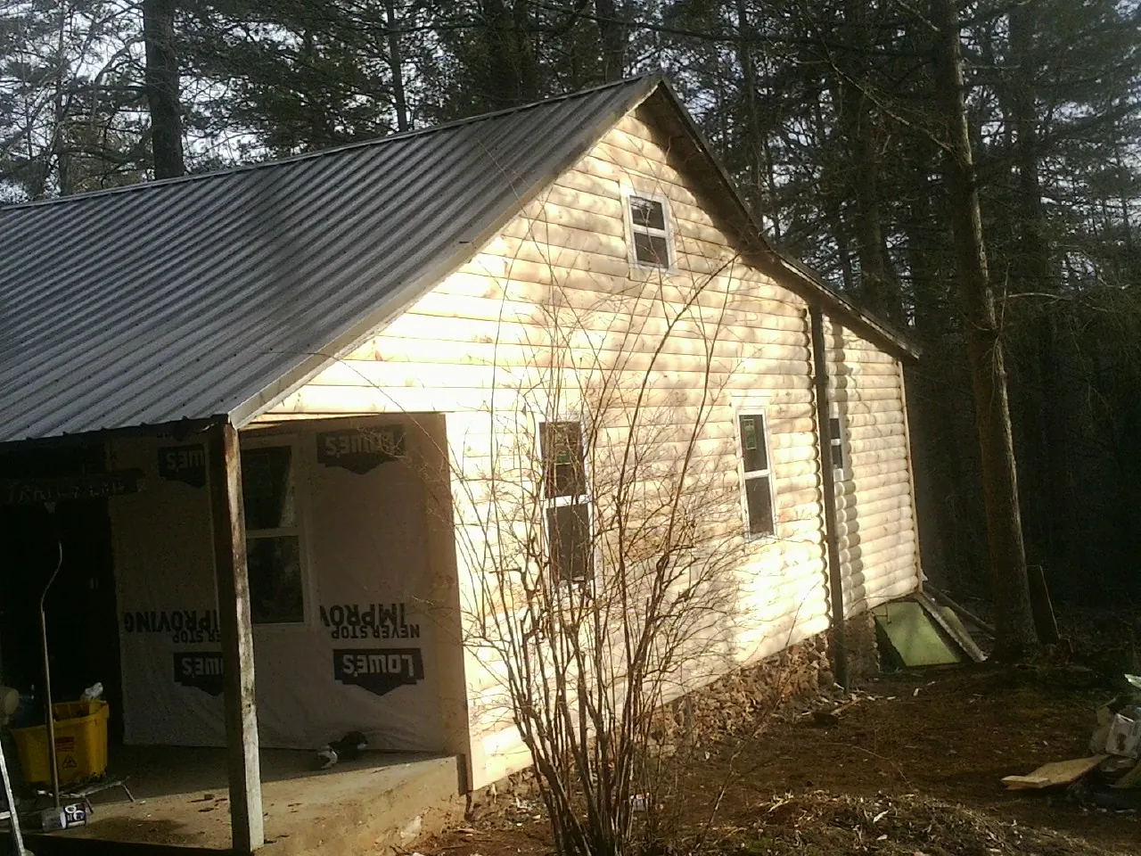 Log siding gable end under a dark metal roof edge in Newtown