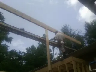 Carpenter setting a ridge beam over a new addition frame — Ice Dam Removal by Roofing Brothers in Newtown
