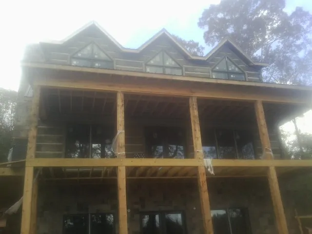 Dormers and porch framing on a large log home under construction — Roof Coating work by our crew in Newtown